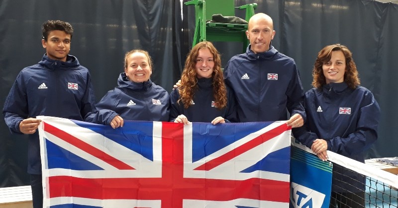 The Great Britain Deaf Tennis Squad holding the Union Jack flag on a tennis court