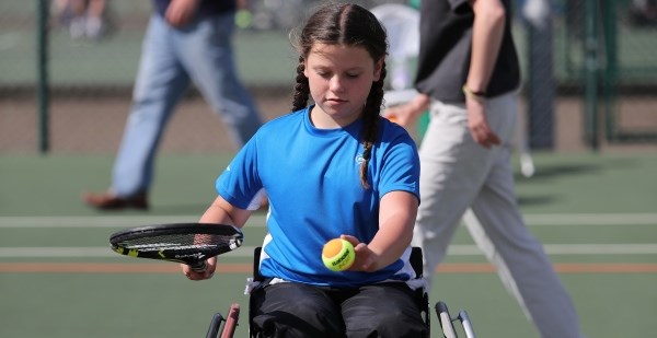 Young girl in wheelchair playing with her racket and ball