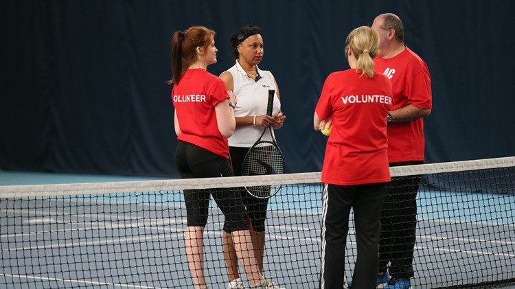 Volunteers with a visually impaired tennis player