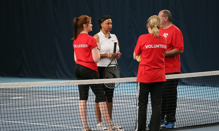Volunteers with a visually impaired tennis player