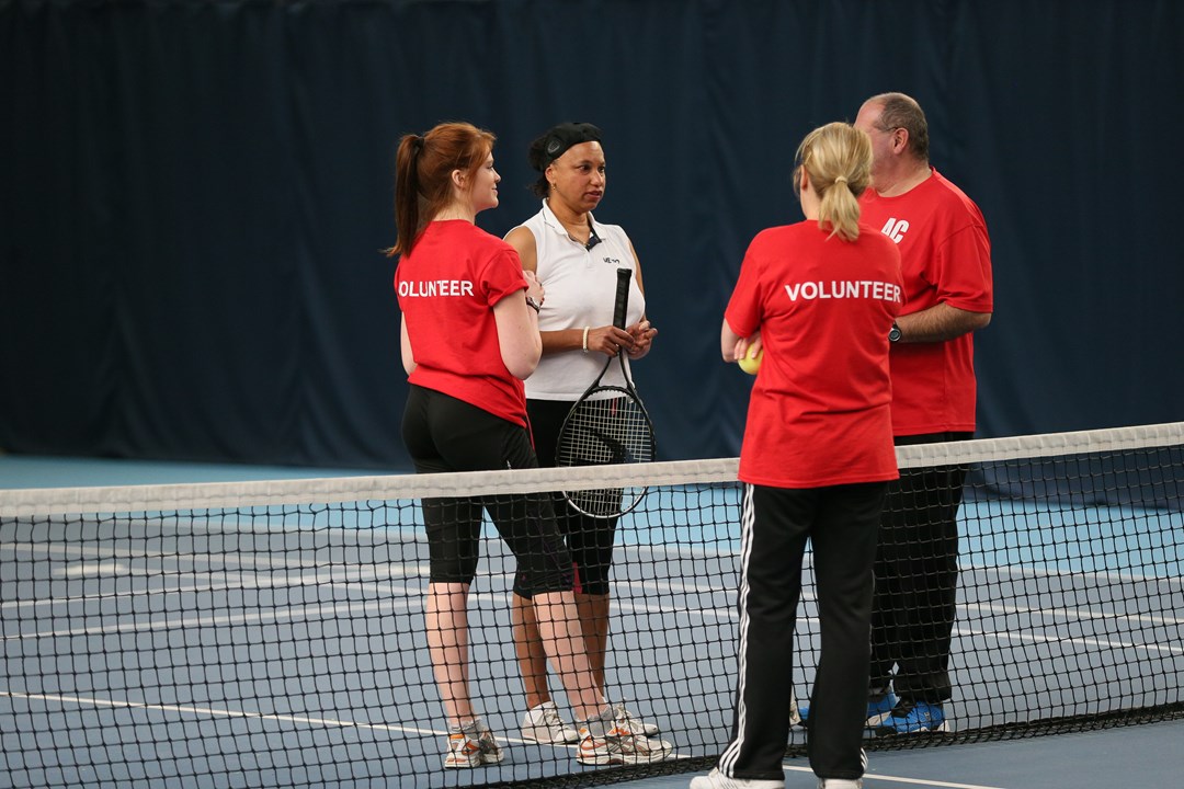 Volunteers with a visually impaired tennis player