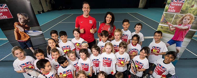 Group of children on a tennis court holding a tennis racket and ball