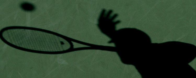 Shadow of a tennis player on a green court