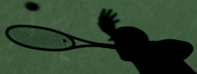Shadow of a tennis player on a green court
