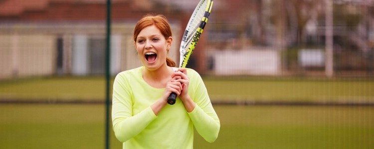 A women who is smiling and playing tennis