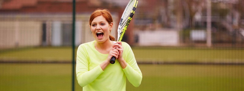 A women who is smiling and playing tennis
