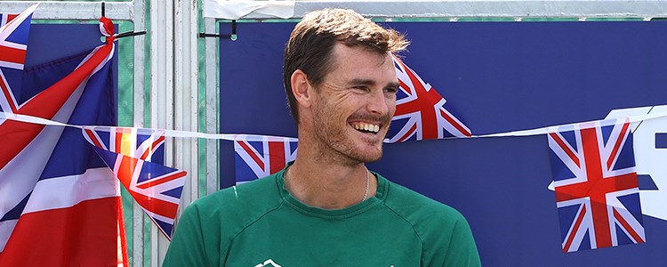jamie murray smiling looking to the side with mini GB flags hanging  and LTA logo behind him 