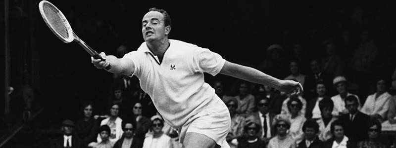 Bobby Wilson returning a shot in a tennis match with people watching