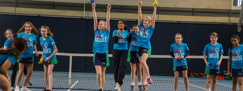 Group of girls cheering on a tennis court