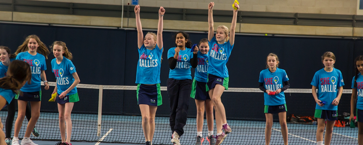 Group of girls cheering on a tennis court