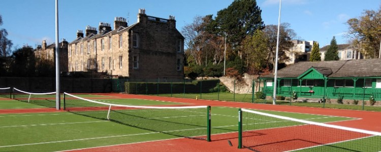 4 artificial grass courts with a wooden pavilion at the back  of the courts and houses to left