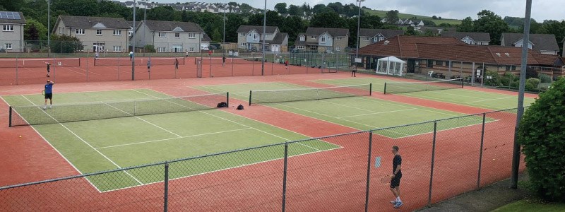 image of grass tennis courts at brought ferry tennis club with two players playing a match on one of the courts