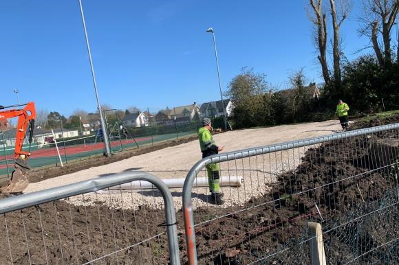 A construction site in front of tennis courts