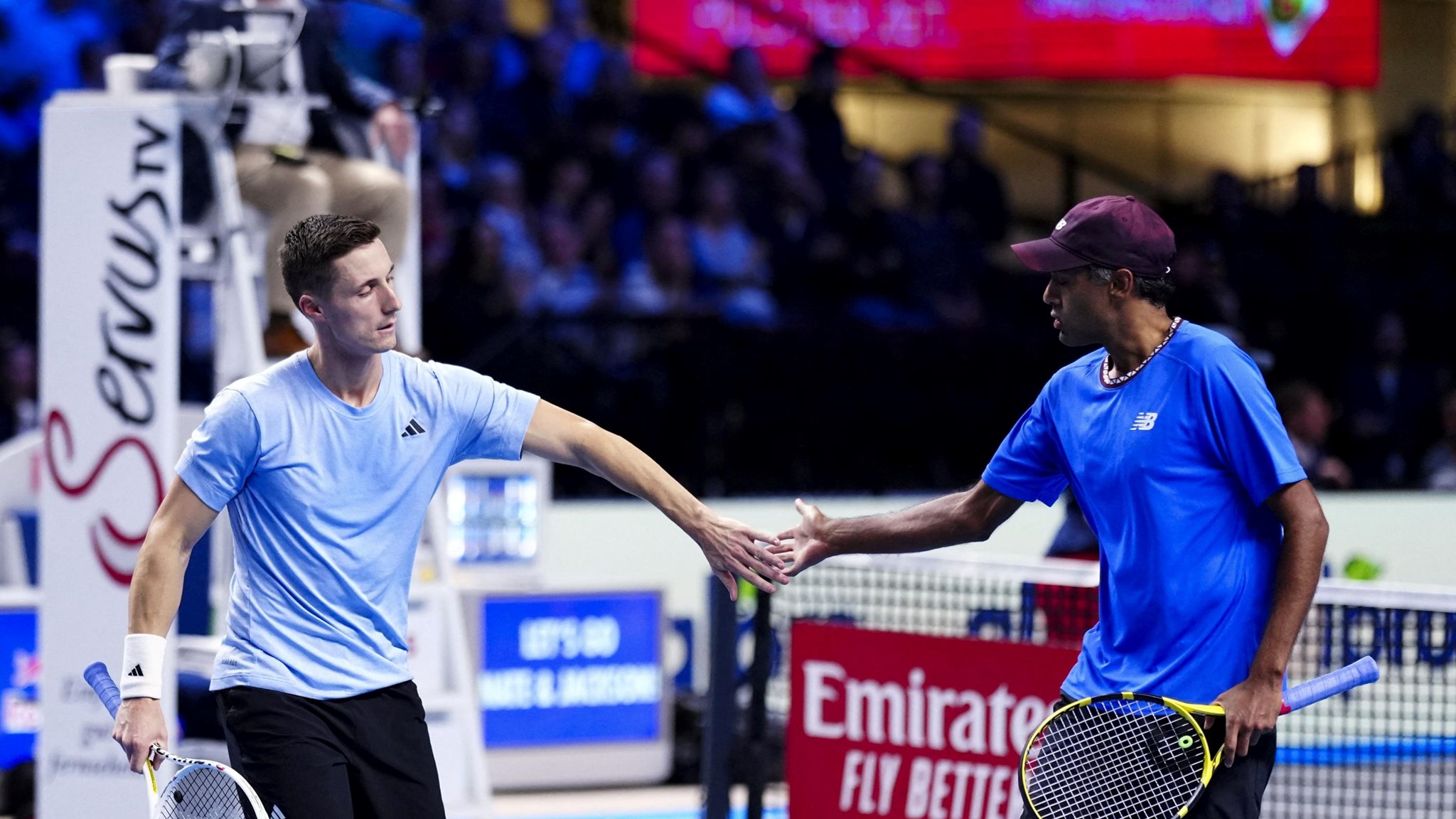 Joe Salisbury and Rajeev Ram high-fiving on court while holding tennis rackets
