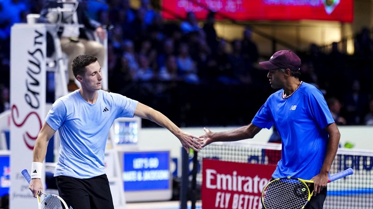 Joe Salisbury and Rajeev Ram high-fiving on court while holding tennis rackets