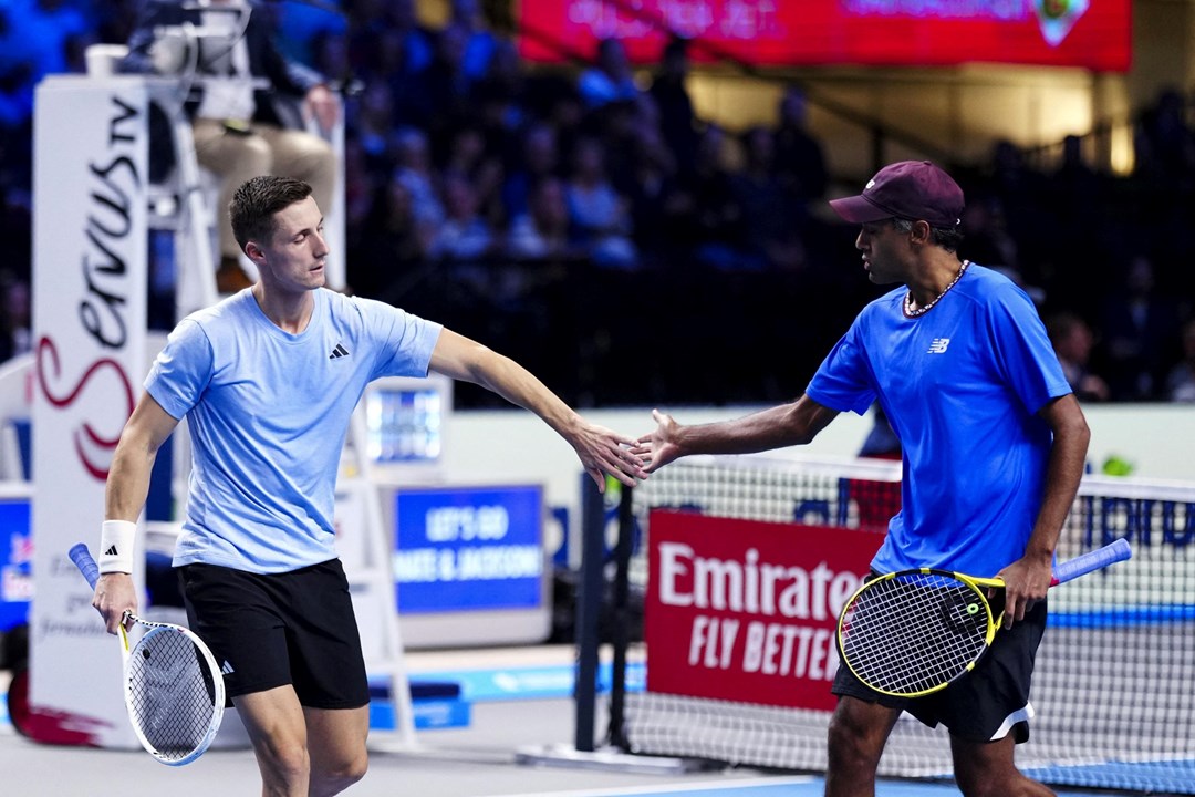 Joe Salisbury and Rajeev Ram high-fiving on court while holding tennis rackets