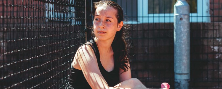 alanna sitting on the floor of the tennis court looking away