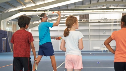 Children watching tennis coach demonstration