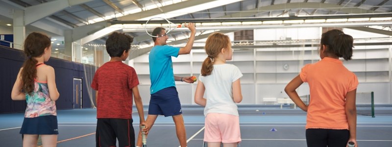 Children watching tennis coach demonstration