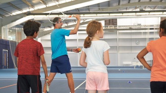 Children watching tennis coach demonstration
