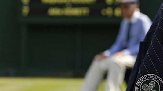 Blurry picture of court with focus on wimbledon badge on officials jacket