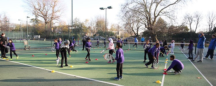 School children playing tennis  on outdoor courts
