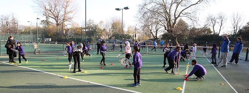 School children playing tennis  on outdoor courts