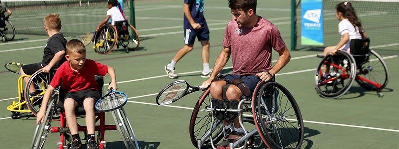 wheelchair adults and juniors rackets in hand practicing skills on tennis courts