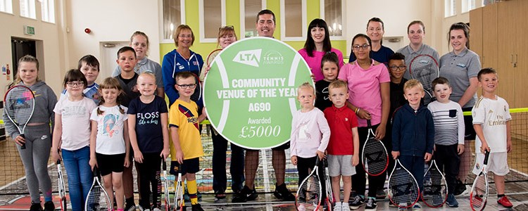 Adults and children holding tennis rackets and a community of the year award