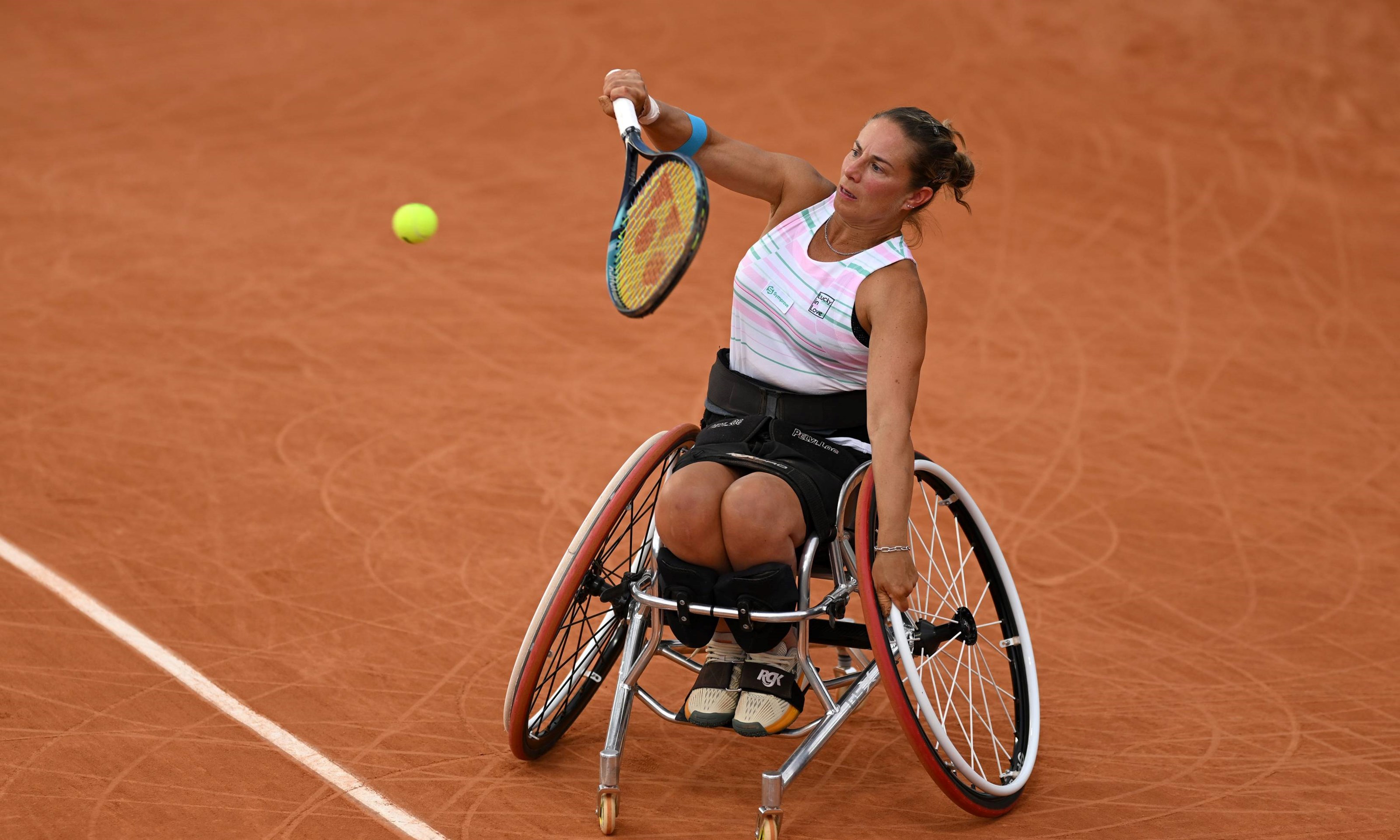Wheelchair tennis player Lucy Shuker hitting a backhand on a clay court while sat in her wheelchair 