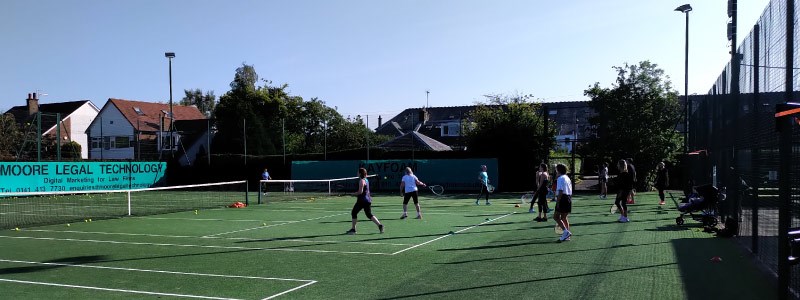 adult players training on two courts at giffnock tennis club