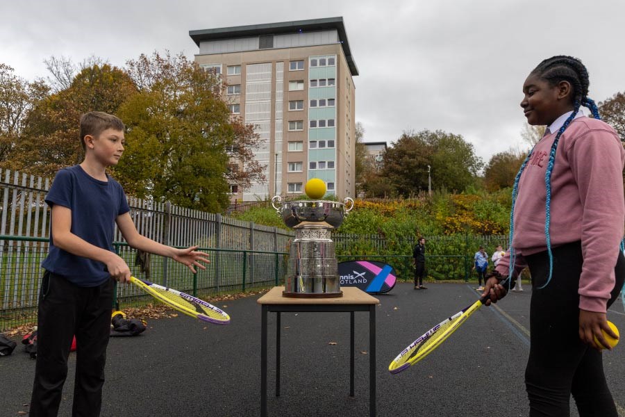 billie jean king cup trophy tour with school children playing outdoor tennis