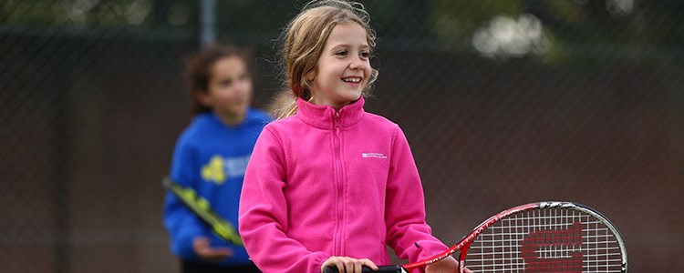 Young girl smiling and playing tennis