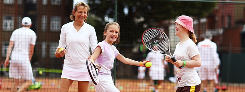 Young girls smiling and laughing playing tennis