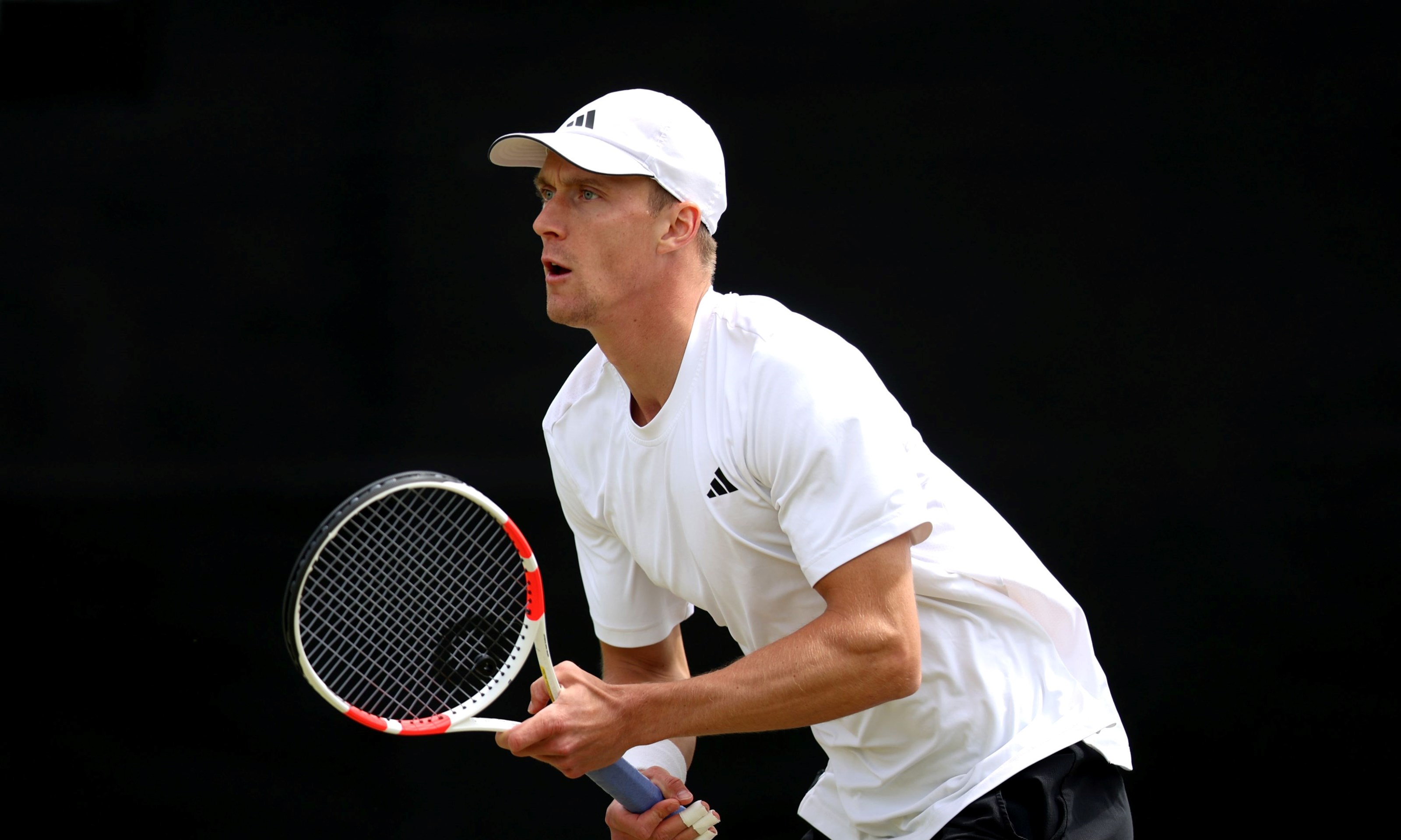 British tennis player holding his tennis racket and preparing to return a serve on court