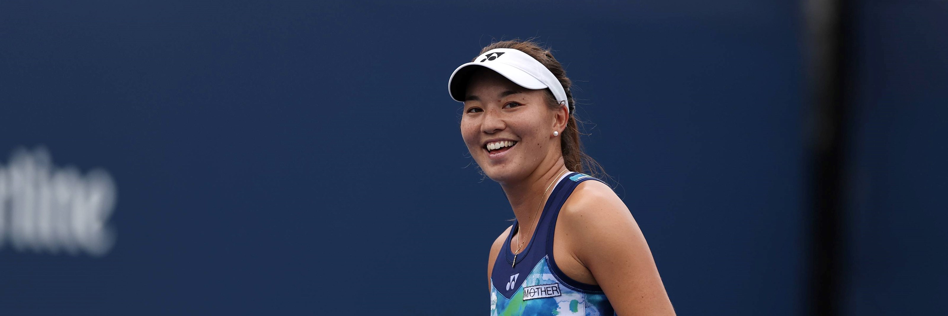 Lily Miyazaki smiling and holding her tennis racket on court at the US Open