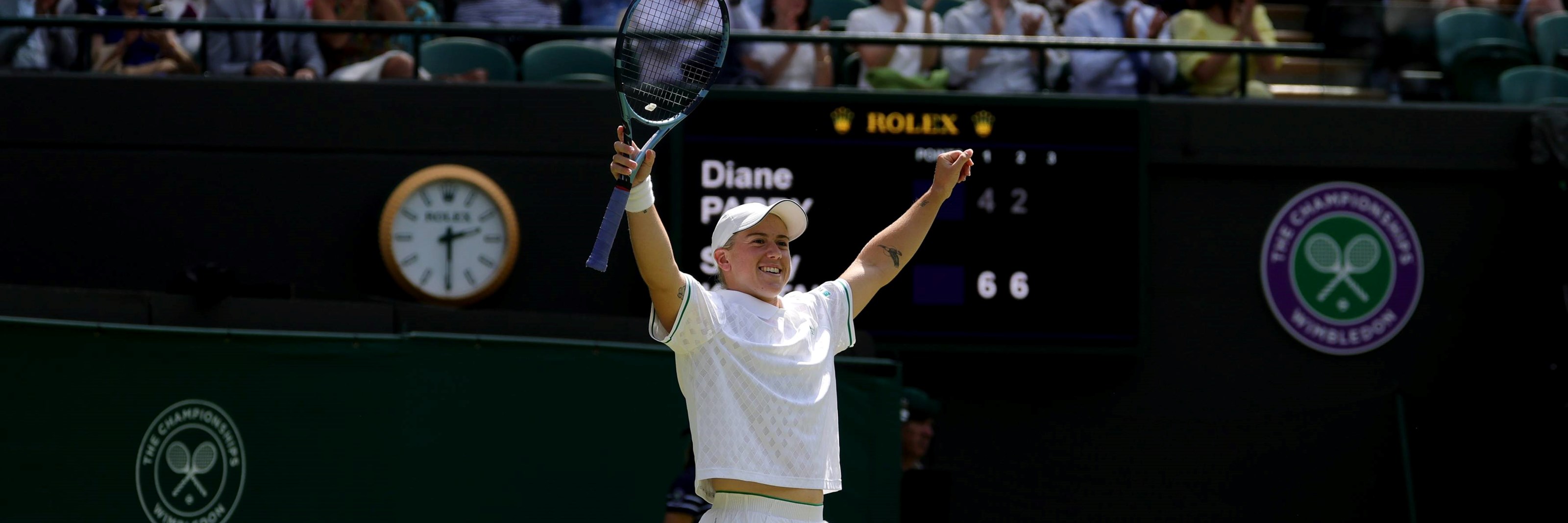 Sonay Kartal holding her hands up in the air with her tennis racket in one hand after beating Diane Parry at Wimbledon 