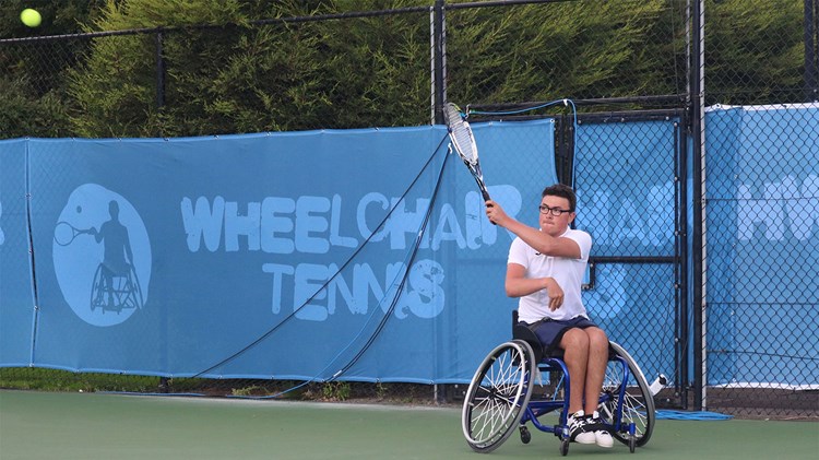 Junior tennis player in wheelchair hits a forehand at the School Games