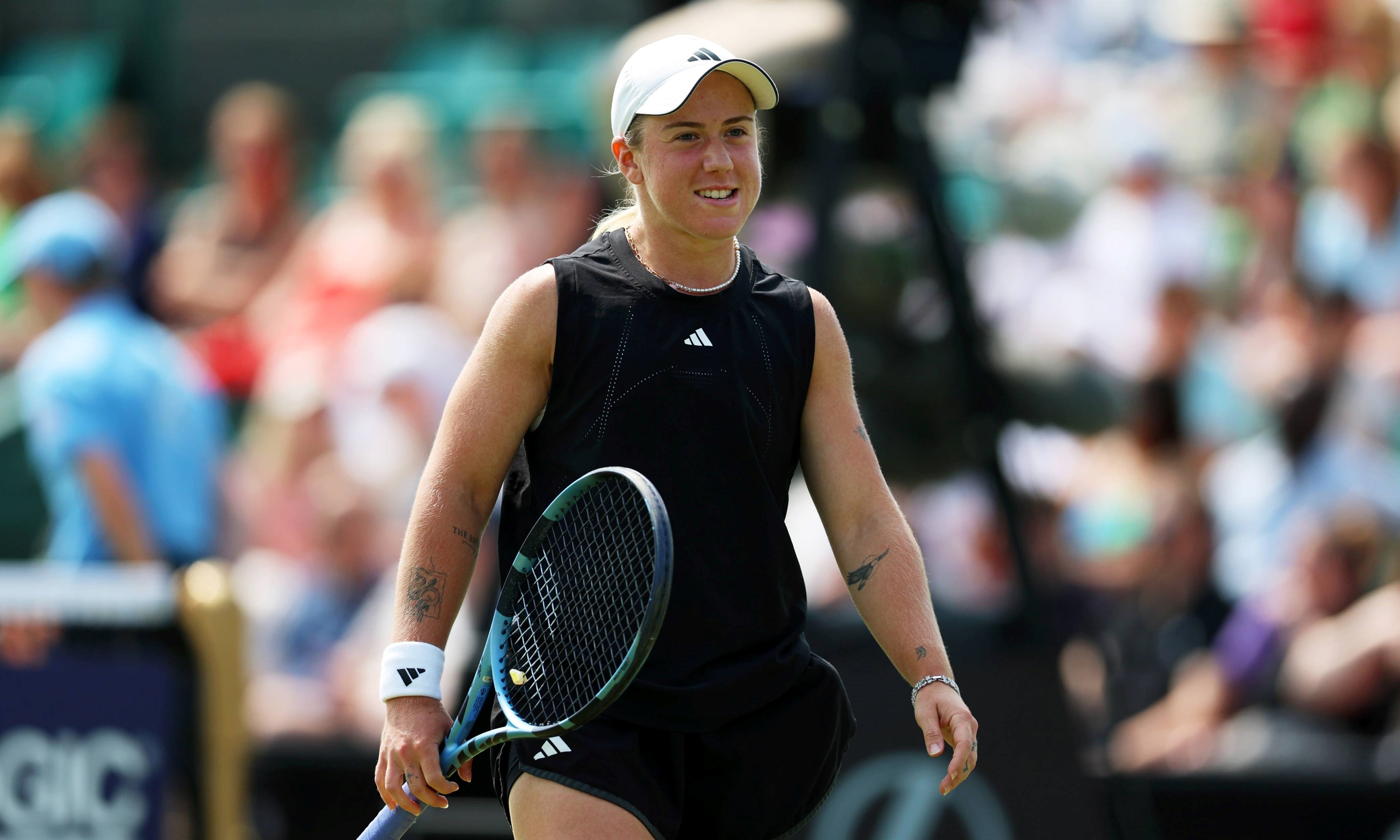 Sonay Kartal smiling and holding her tennis racket on court at the Lexus Eastbourne Open