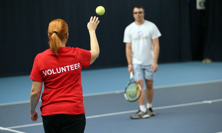 Volunteer helping visually impaired tennis players