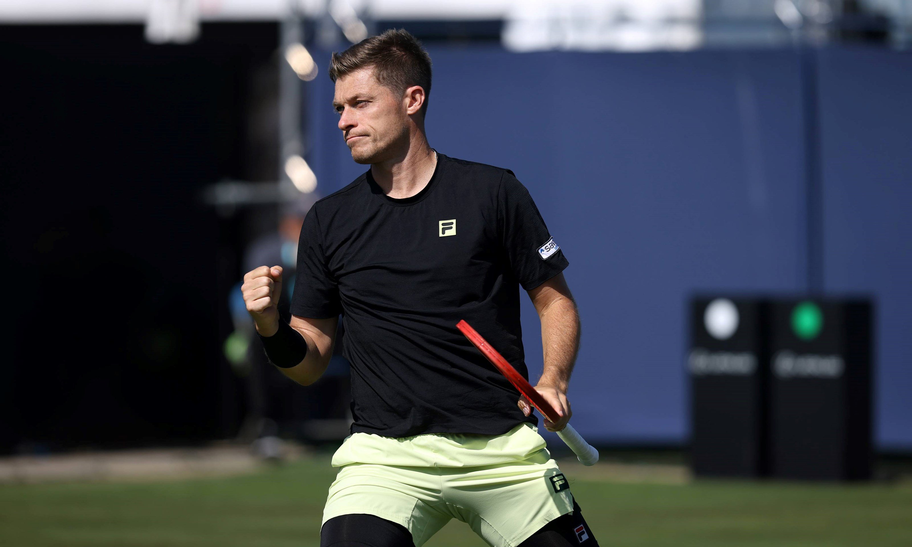 British tennis player Neal Skupski clenching his fist and holding his tennis racket in one hand while on court at the Lexus Eastbourne Open