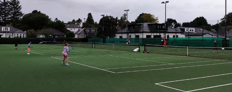 players playing a match on three of the grass courts at giffnock tennis club