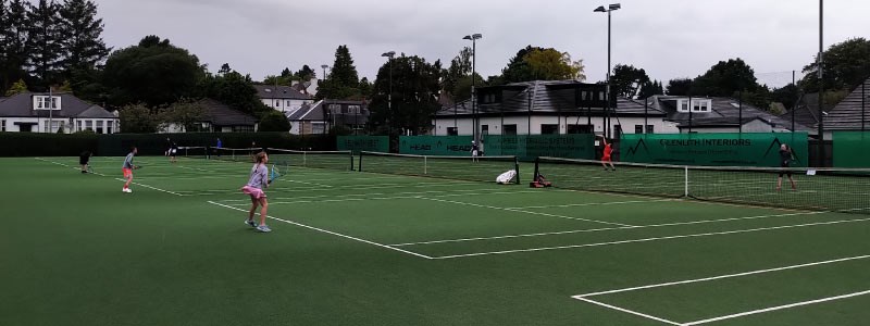 players playing a match on three of the grass courts at giffnock tennis club