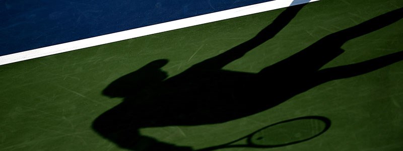 a shadow of a tennis player on a court
