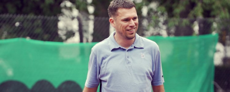 Steve mccann standing on a tennis court wearing a blue shirt and smiling 