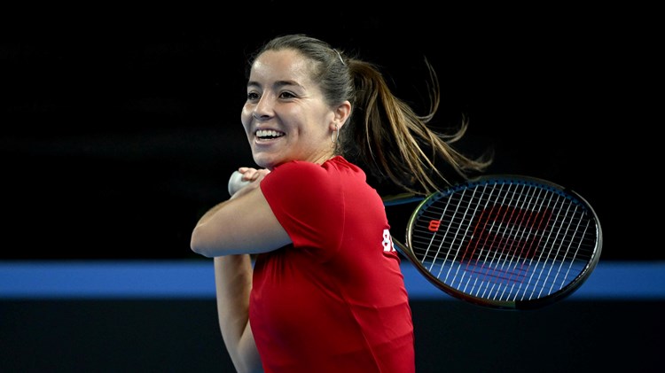 Jodie Burrage smiling on court while hitting a backhand