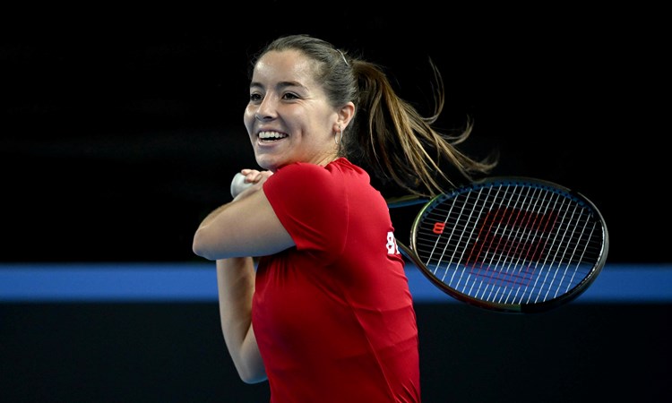 Jodie Burrage smiling on court while hitting a backhand