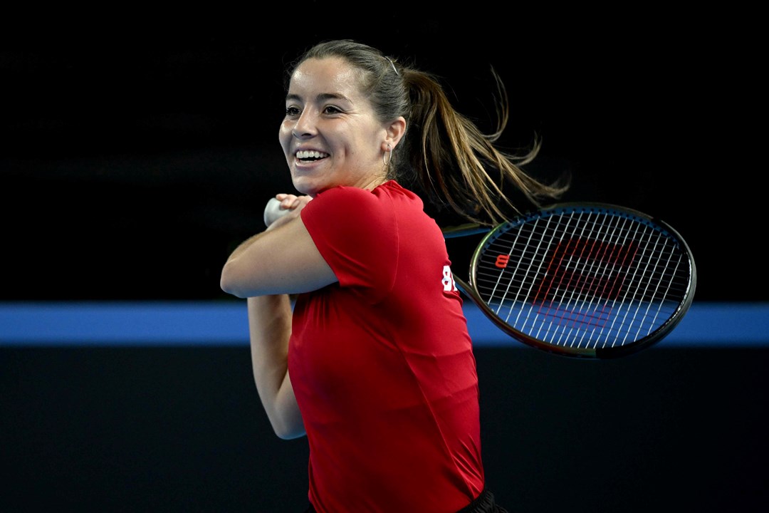 Jodie Burrage smiling on court while hitting a backhand