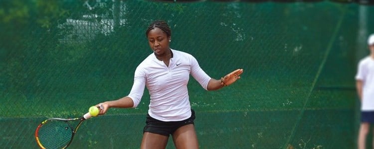 Woman playing tennis with a person in the background