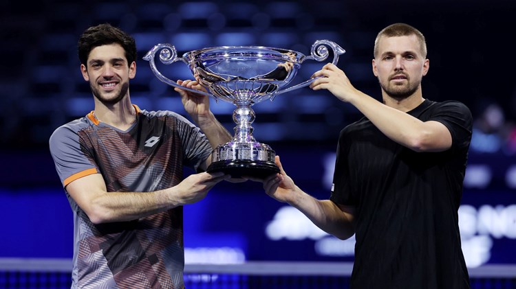 Julian Cash and Lloyd Glasspool smiling while holding the ATP year-end doubles No.1 trophy on court at the Nitto ATP Finals